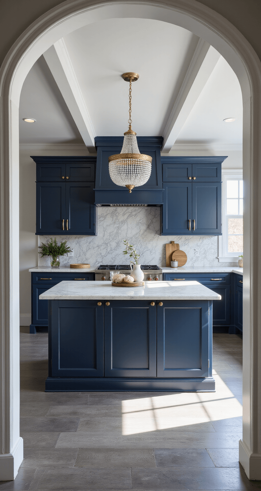 Navy Kitchen Cabinets: A Comprehensive Style Guide for Stunning Interiors Transitional navy kitchen featuring coffered ceiling, bright indirect sunlight, navy inset cabinets with brass and chrome accents, white marble counters with dramatic veining, geometric grey and white tile backsplash, crystal chandelier over the island, and grey wood-look tile flooring, viewed from the entrance.