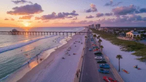 Daytona Beach in April: Your Ultimate Sun-Soaked Adventure Guide (Without the Tourist Traps!) "Aerial view of Daytona Beach at sunset in spring, featuring gentle waves, golden sand, lined up classic cars, beach activities, the Bandshell concert, and a vibrant sky."