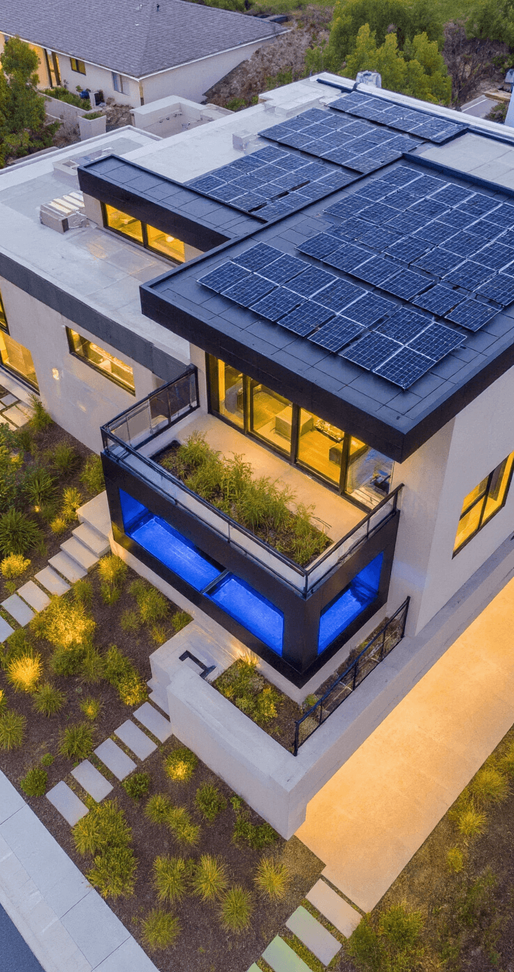 Modern Florida Home Exterior: A Stunning Design Guide for 2025 A dusk exterior view of a sustainable home featuring sleek black solar panels on a flat roof, a concealed rainwater collection system, and illuminated windows showcasing smart home features. Cool blue LED landscape lighting highlights native plantings, captured from an elevated drone perspective with a long exposure for balanced ambient light.