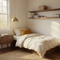 Cinematic wide-angle shot of a cozy corner bedroom with cream linen bedding, walnut floating nightstand, white dresser, and warm golden hour sunlight casting soft shadows on hardwood floors.
